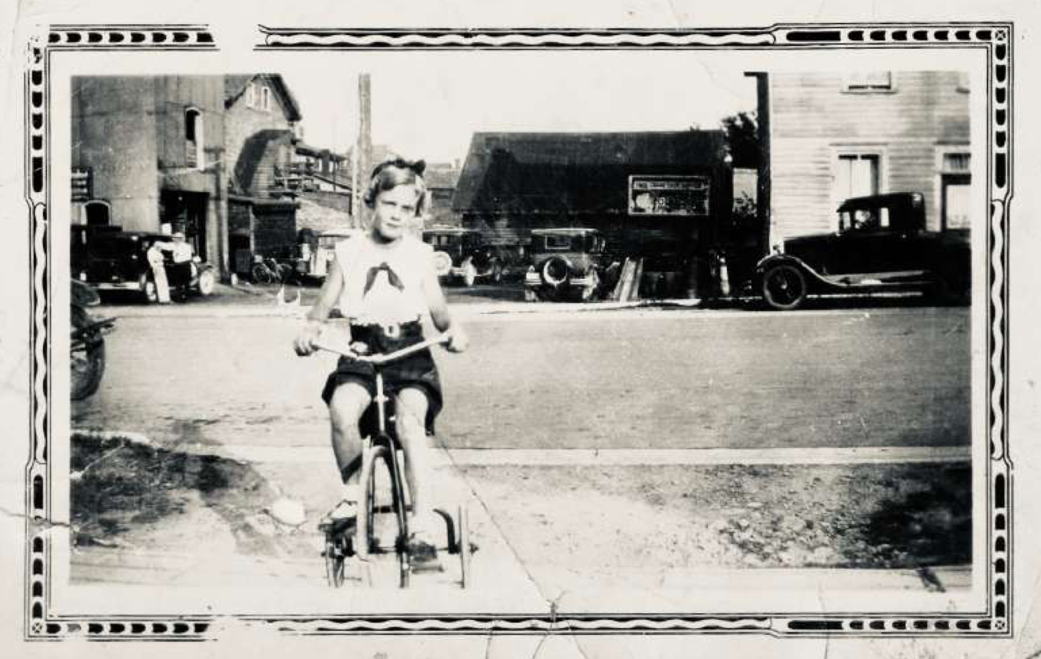 Jacqueline Stunden on a tricycle with Whitaker’s garage in the background. | Oakville Historical Society
